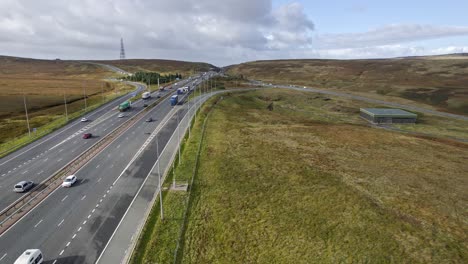 drohnenaufnahmen, die den verkehr auf der m62 am windigen hügel in gesprenkeltem sonnenlicht am höchsten punkt in den pennine hills, yorkshire, vereinigtes königreich, zeigen