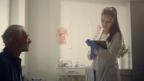 doctor using tablet examination senior man in clinic. woman consulting patient.