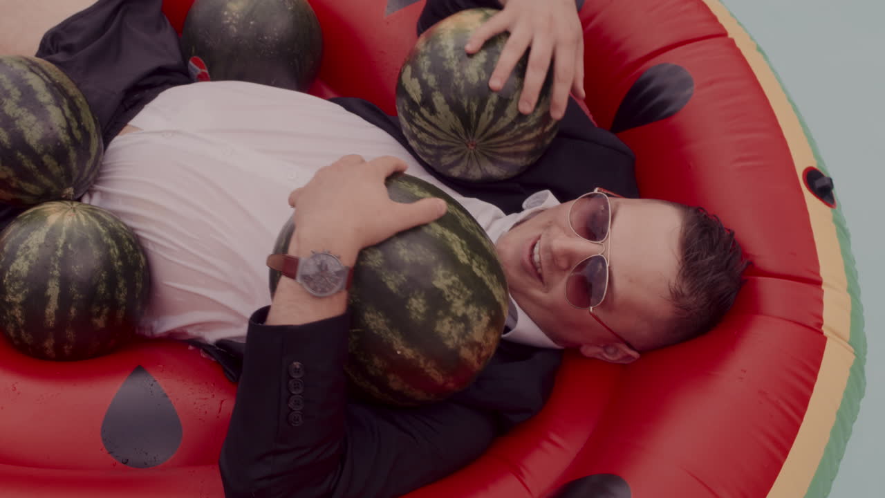 Man in suit relaxing on a watermelon pool float