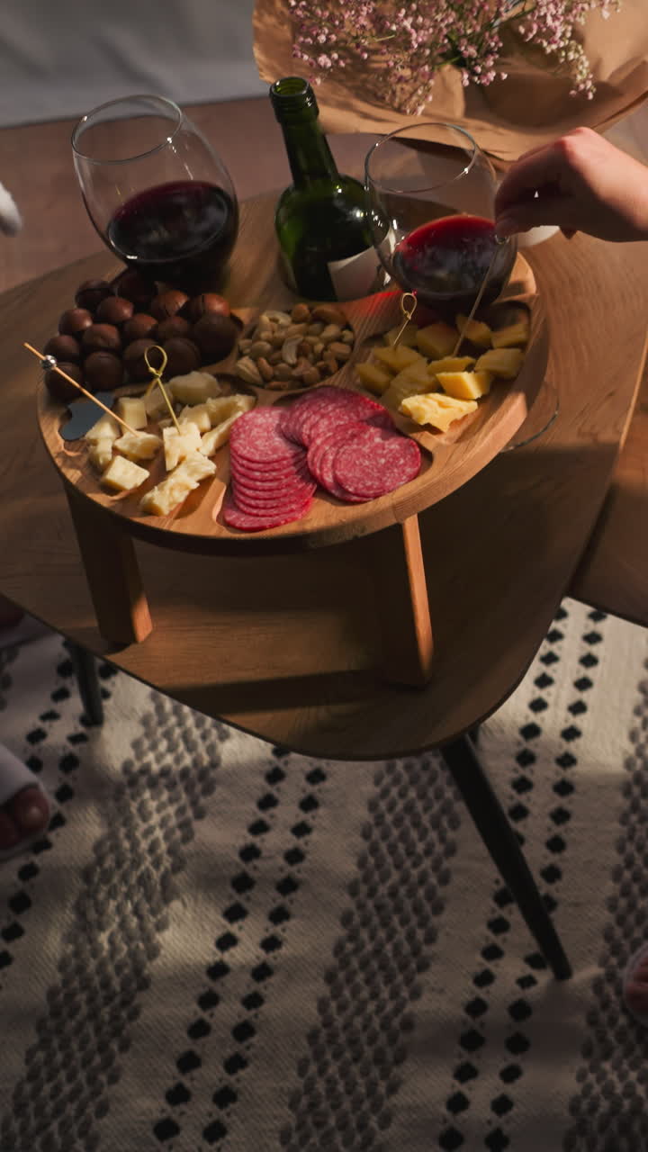 Woman tries out snacks on glamping terrace. Wooden wine table with delicious appetizer for gourmets. Relaxed lady in terry bathrobe enjoys evening at round house