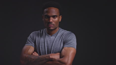 Studio-Portrait-Of-Male-Athlete-Sport-Training-Or-Exercising-In-Gym-Folding-Arms-Against-Black-Background