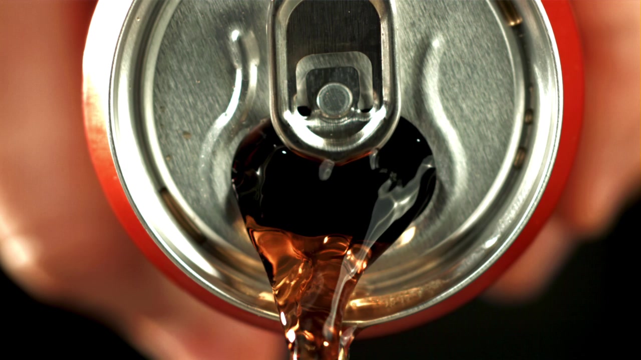 Primo piano di cola che si versa da una lattina di bibita rossa