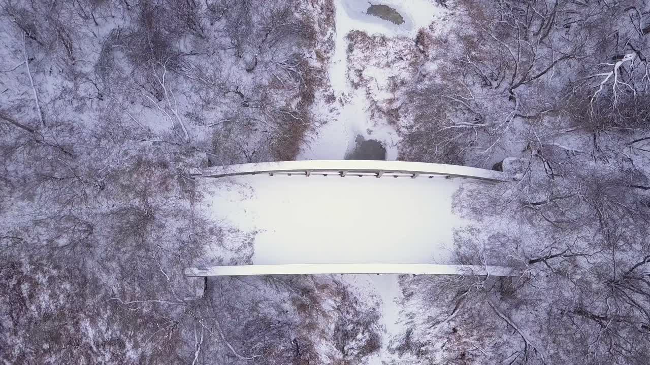 Bird's eye view of snowy, abandoned highway bridge over frozen river
