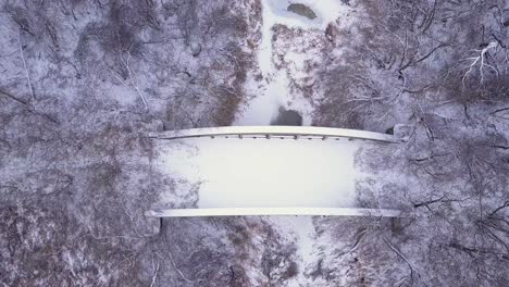 Vista-De-Pájaro-Del-Puente-De-Carretera-Abandonado-Y-Cubierto-De-Nieve-Sobre-Un-Río-Congelado