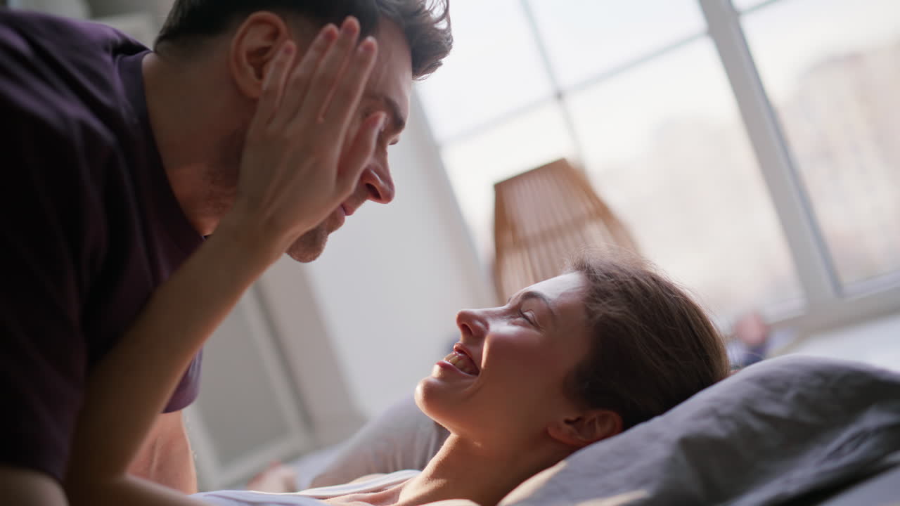 Sleeping woman awakened husband at sunlight flat closeup. Happy morning couple