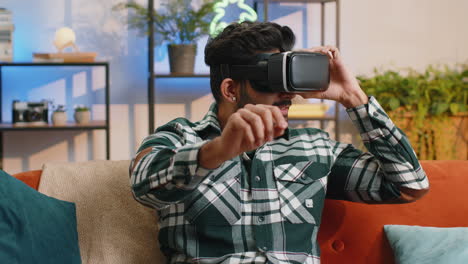 Man-using-virtual-reality-futuristic-technology-headset-to-play-simulation-3D-video-game-at-home