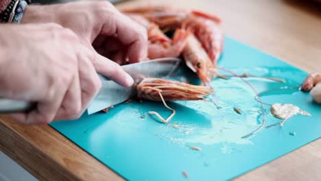 chef quitando cuidadosamente una cabeza de camarón preparando camarones para cocinar con pasta