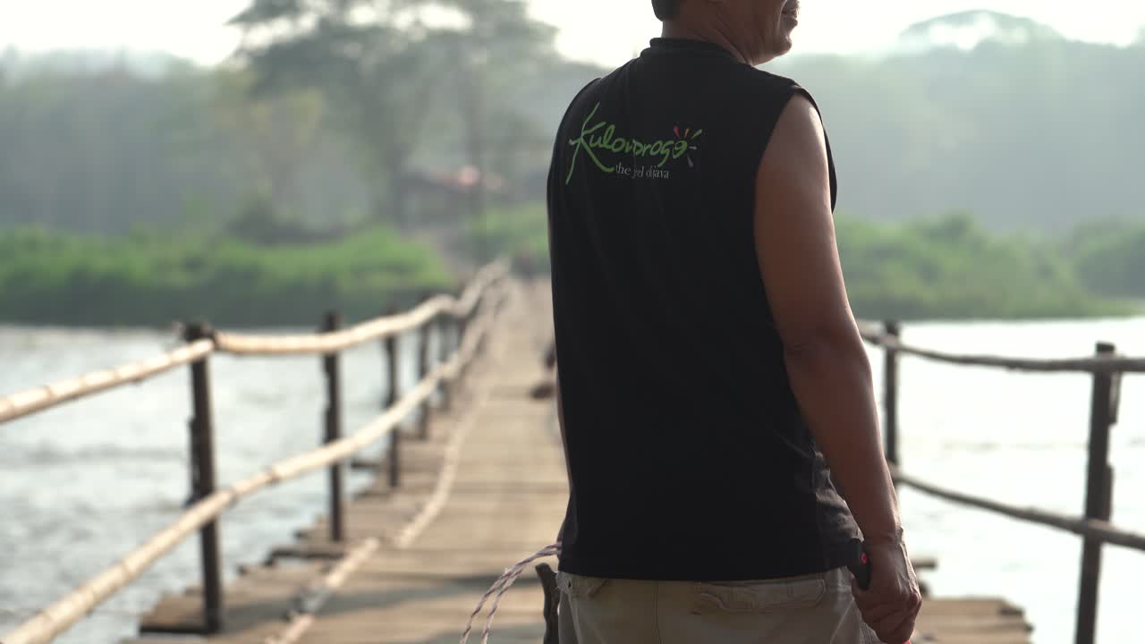 A group of people are maintaining and repairing a bridge made of wood. The bridge connects the villages of Bantul and Kulonprogo.