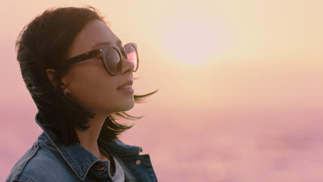 portrait of beautiful asian woman smiling enjoying carefree lifestyle exploring freedom on vacation looking happy with wind blowing hair wearing sunglasses