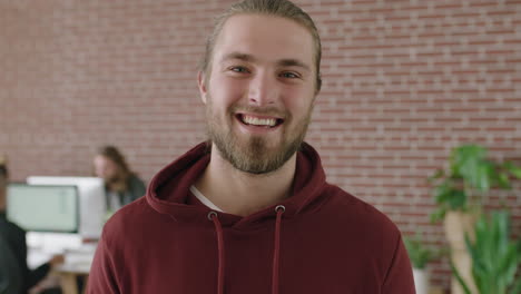 portrait of happy young man in office internet cafe smiling cheerful pensive at camera wearing hoodie successful male entrepreneur