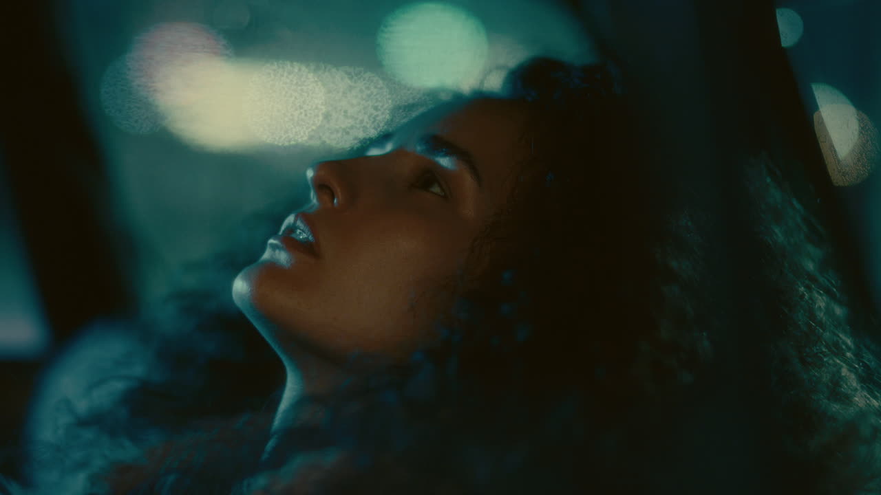Giovane donna malinconica appoggiata all'indietro che guarda in alto in auto di notte