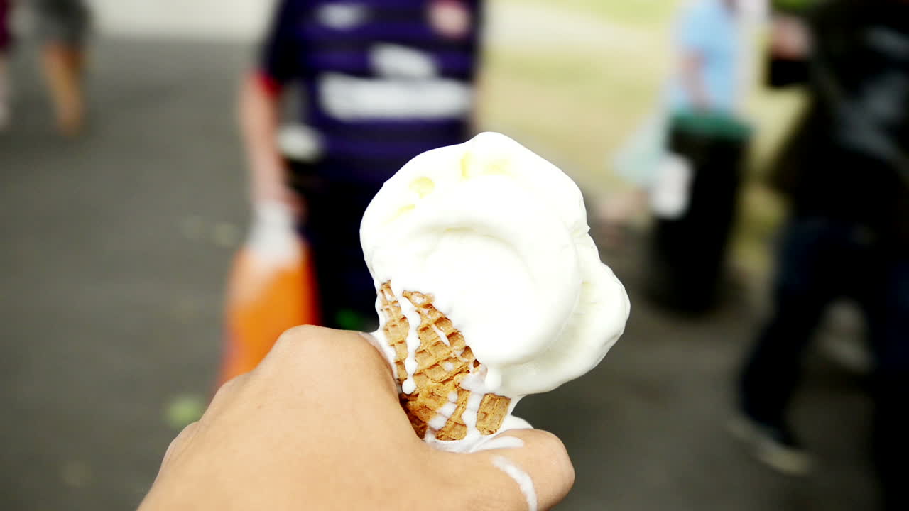 Punto di vista di un uomo con gelato, mentre una donna mangia camminando in città