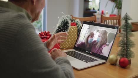 Hombre-Mayor-Caucásico-En-Videollamada-Con-Amigas-Mayores-Con-Máscaras-Faciales-En-Navidad