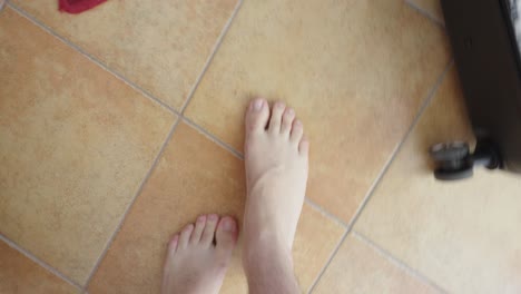 close-up of a man’s bare feet slowly walking on a tiled floor indoors. everyday movement symbolizing morning routine, casual lifestyle, or natural human steps