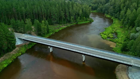 Zoom-out-shot-of-a-bridge-in-over-the-river-channel-situated-within-the-dense-forest