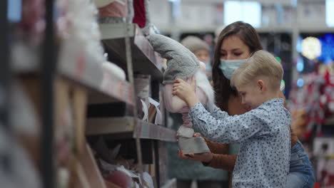 Mom-in-protective-mask-with-boy-picks-up-a-toy-in-a-mall-on-Christmas-Eve-during-the-pandemic