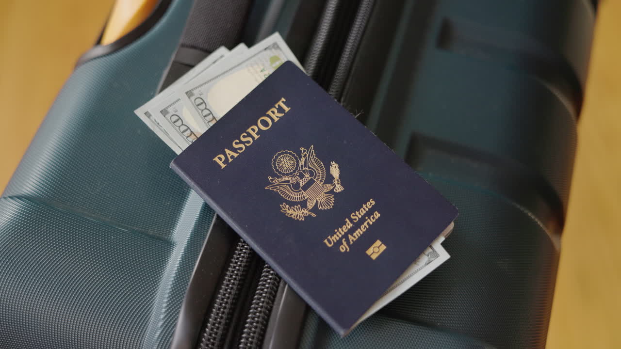Passaporto statunitense e banconote da un dollaro appoggiati su una valigia