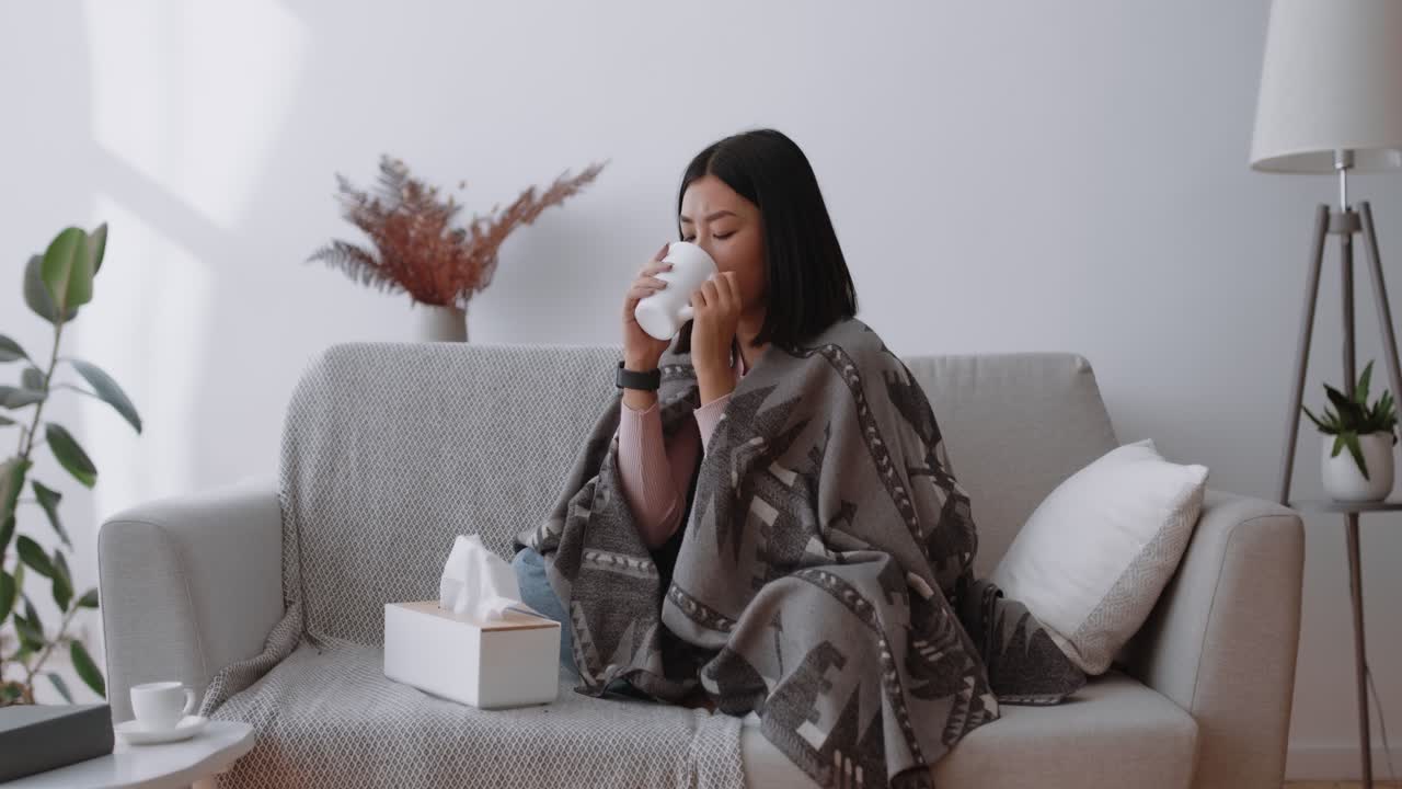 Woman Sitting on Couch with a Blanket Drinking Tea