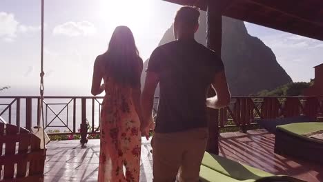 a romantic man and woman couple on vacation toasting drink on the balcony of a luxury resort hotel room in st lucia caribbean islands