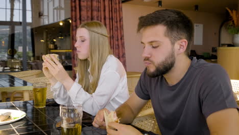 Vista-De-Cerca-De-Una-Mujer-Y-Un-Hombre-Hablando-Y-Comiendo-Pizza-Con-Sus-Amigos-En-La-Mesa-Del-Restaurante