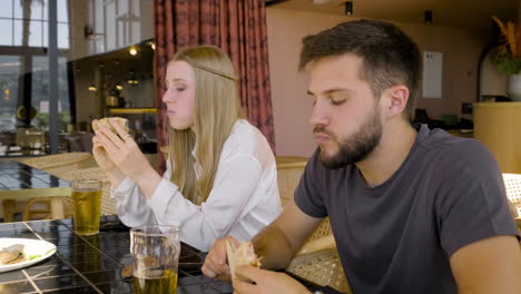 vista de cerca de una mujer y un hombre hablando y comiendo pizza con sus amigos en la mesa del restaurante