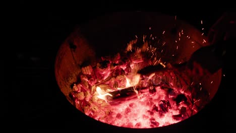 male hand prepping coals for cooking in a weber