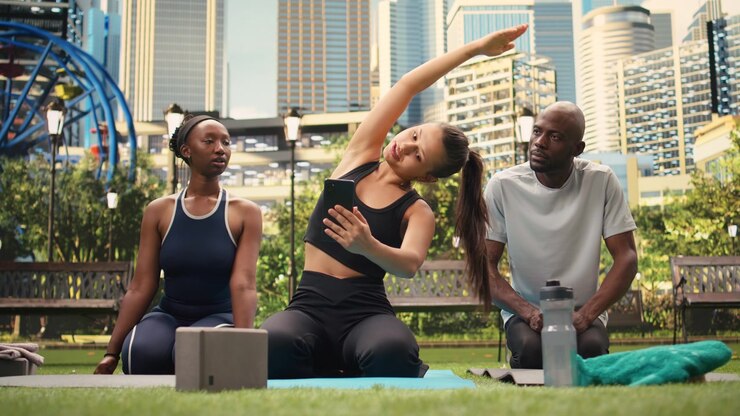 Woman shows content on smartphone to yoga participants as they sit together