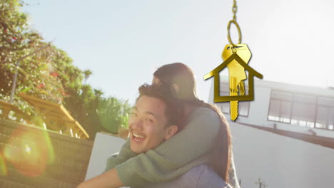 Animation-of-gold-house-key-and-key-fob-over-happy-biracial-couple-by-house