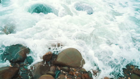 Ocean-white-wash-and-waves-slowly-crashing-over-rocks-and-stones-in-cornwall,-england,-120fps-slow-slow-motion