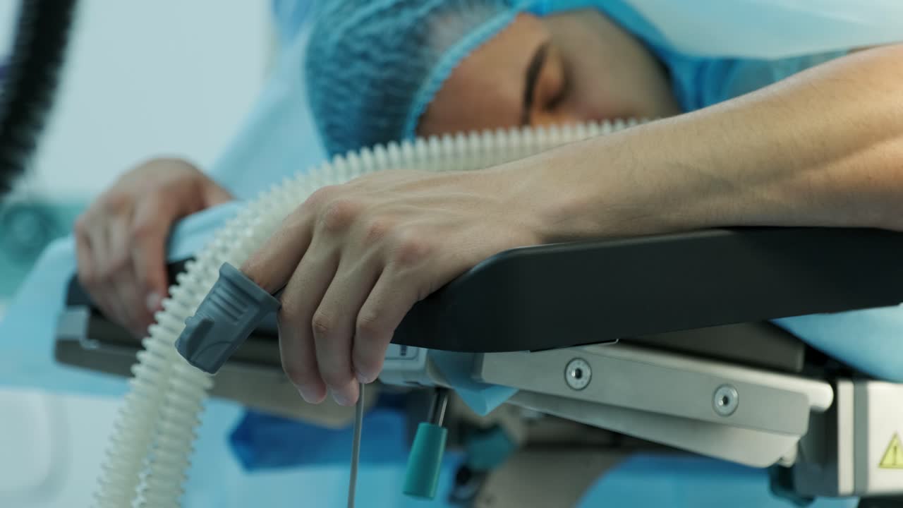 el paciente se acuesta en la mesa de operaciones con un sensor en el dedo