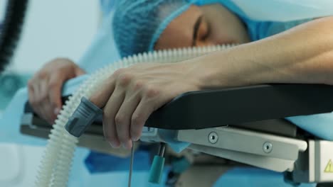 el paciente se acuesta en la mesa de operaciones con un sensor en el dedo