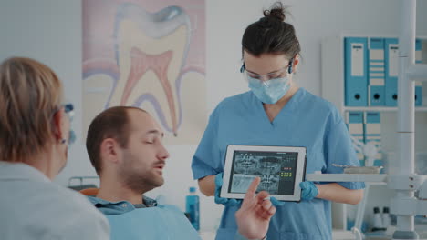 nurse and patient analyzing denture radiography in dentistry cabinet