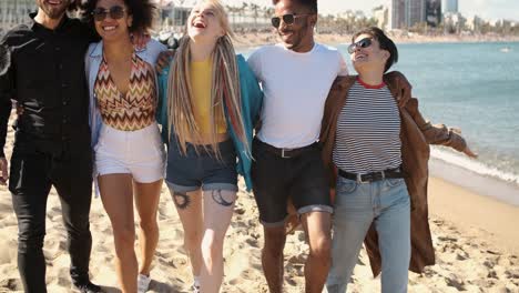 happy diverse friends walking on beach in embrace