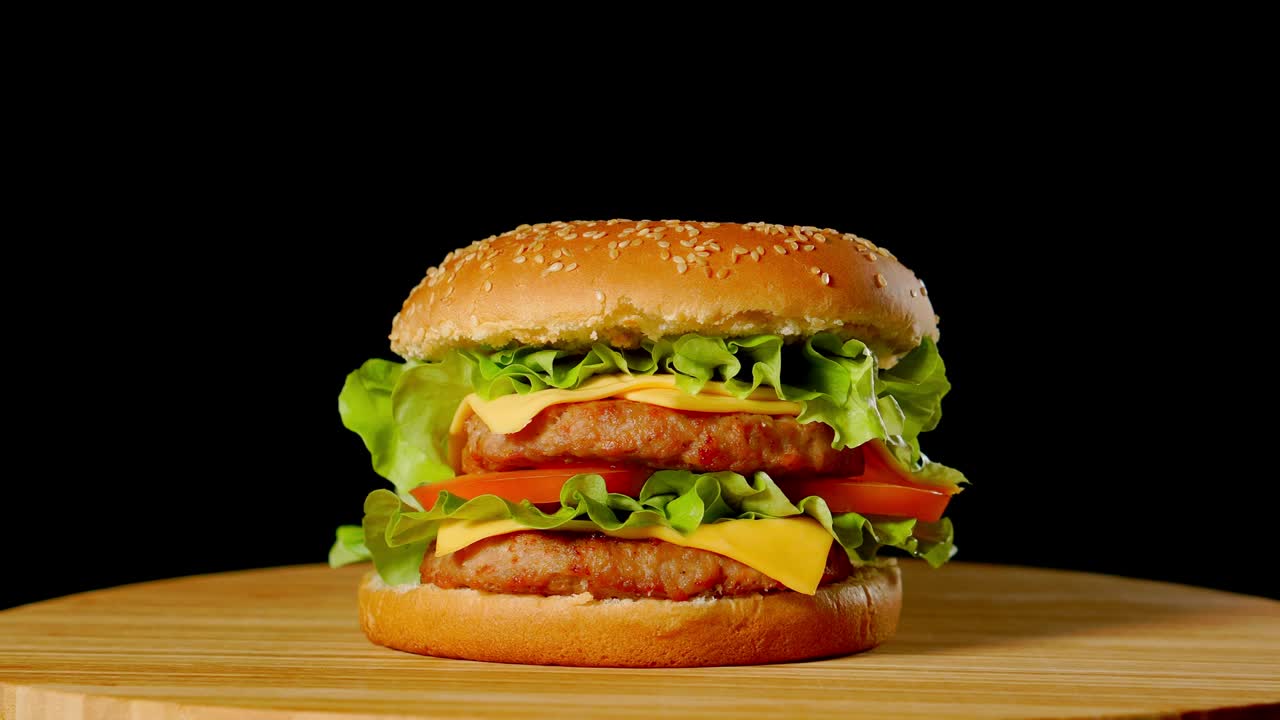 hamburguesa fresca y apetitosa girando sobre un fondo negro.