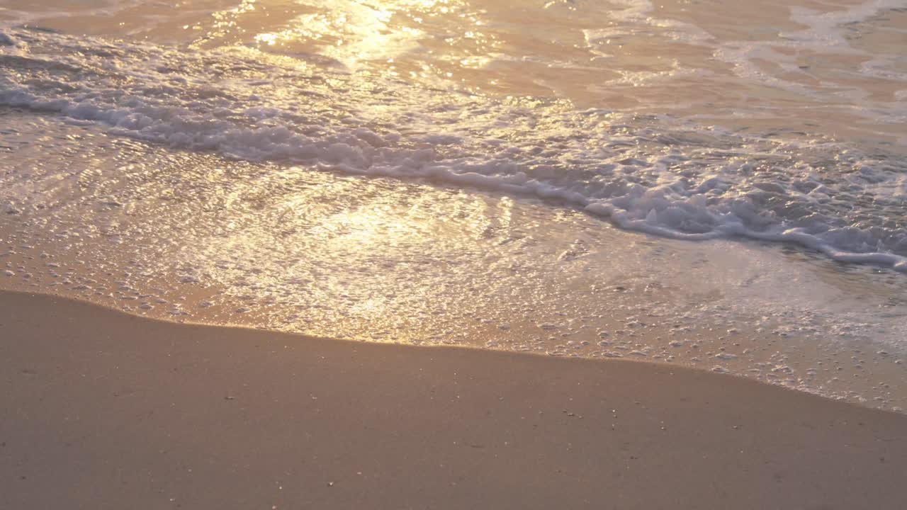 파도와 모래는 일몰, 슬로우 모션으로 황금빛으로 빛납니다.