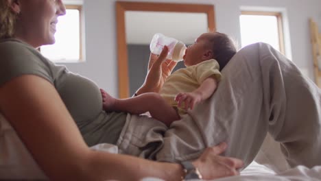 Video-Einer-Glücklichen-Kaukasischen-Mutter,-Die-Ihr-Neugeborenes-Baby-Mit-Der-Flasche-Auf-Dem-Bett-Füttert