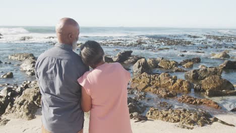 happy senior african american couple embracing at beach, copy space, slow motion