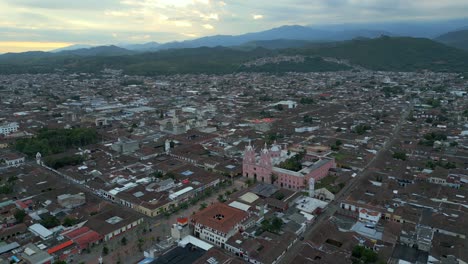 aerial view of a city with a pink church and mountains in the background
