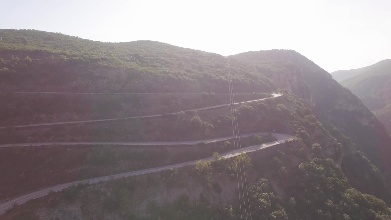 AERIAL car driving at a road at green mountains curvy road travel lifestyle freedom cinematic mood sunny day scenic drone shot top view inside forest lonely travel lifestyle