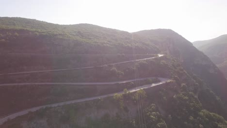 aerial car driving at a road at green mountains curvy road travel lifestyle freedom cinematic mood sunny day scenic drone shot top view inside forest lonely travel lifestyle