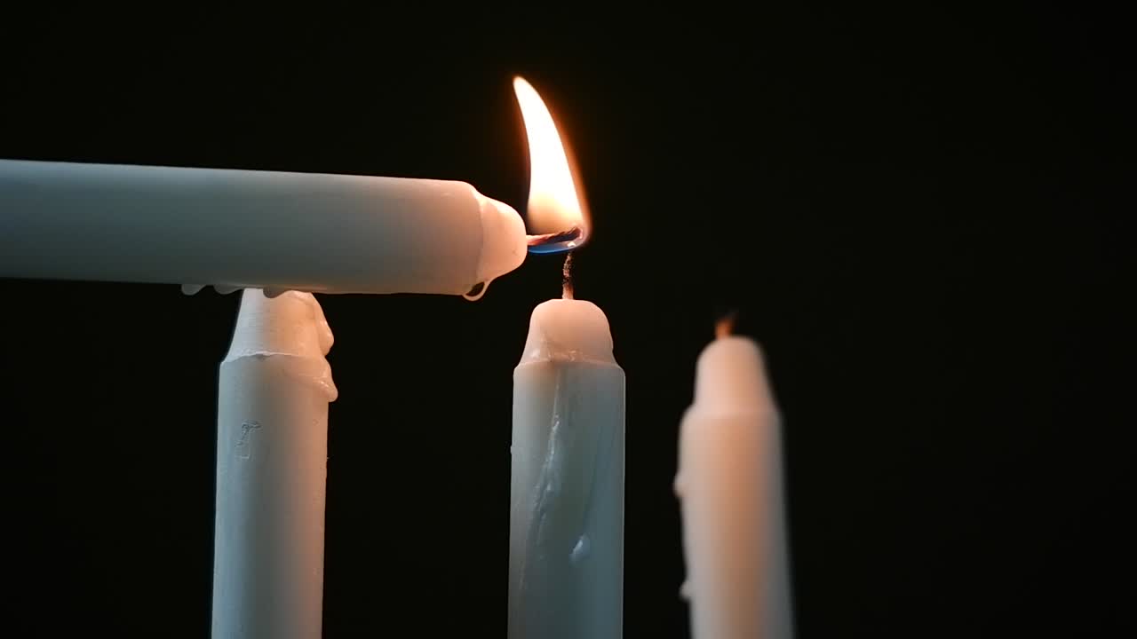 candela bianca bruciata in una stanza buia