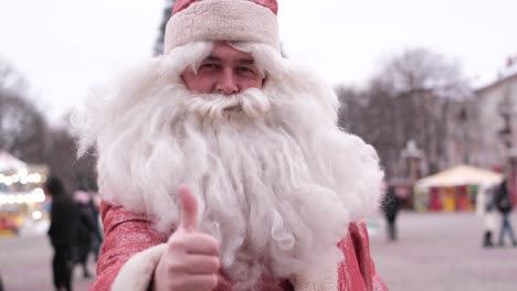 smiling santa claus showing thumb up super sign smiling santa claus showing thumb up super sign sanda on the street near the christmas tree merry christmas and happy new year