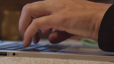 fingers typing on laptop keyboard, close up, pan left to right