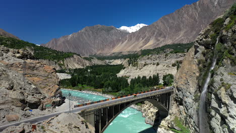 drone shot of turquoise blue water river flowing under a bridge in karakoram mountain range along karakoram highway, slowly revealing