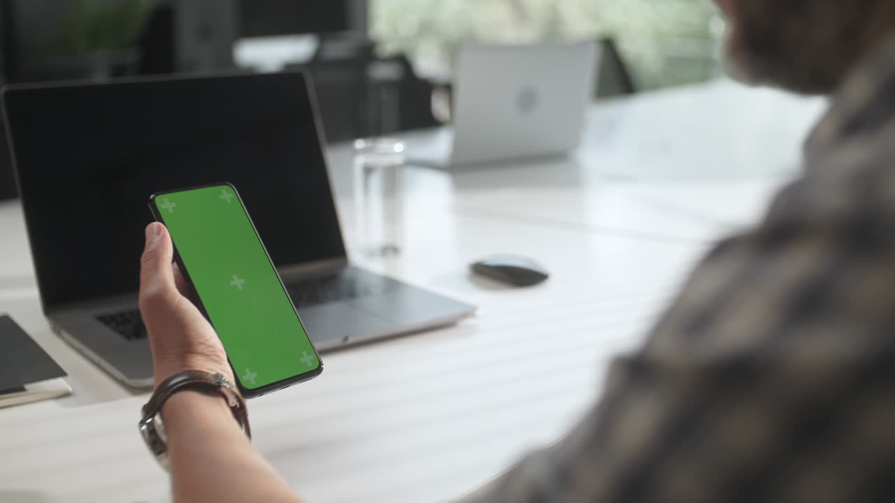 hombre de negocios manos trabajando internet en el teléfono en el escritorio. hombre en el teléfono con pantalla verde para el espacio de copia. chromakey maquillaje sin marcadores de seguimiento