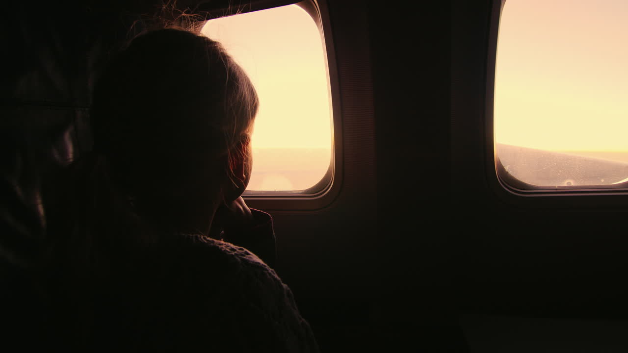 비행기에 앉아 떠오르는 태양을 창밖으로 내다보는 소녀