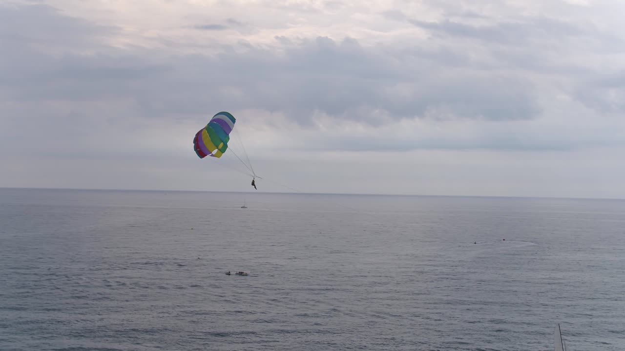 una vista de pájaro de personas haciendo parasailing en lo alto de un océano en calma en un día nublado