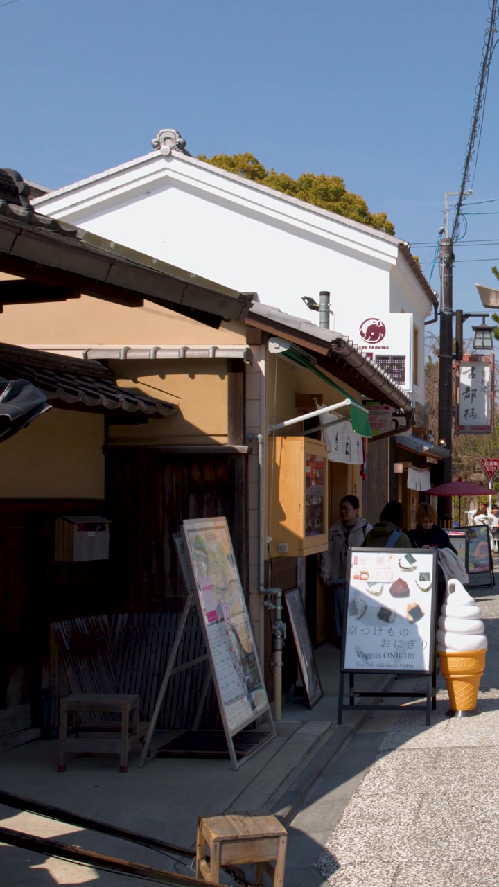 明るい日差しの下、伝統的な日本の建物と店先の静止したワイドショット