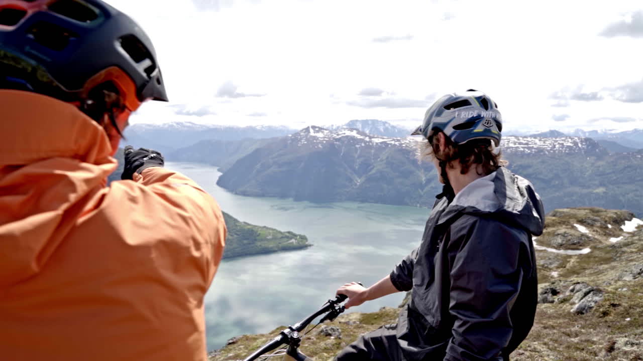 Epic mountain biking adventure above the fjords near Sogndal, Norway. Rider tackles rugged trails surrounded by dramatic cliffs, lush green hills, and stunning Nordic scenery