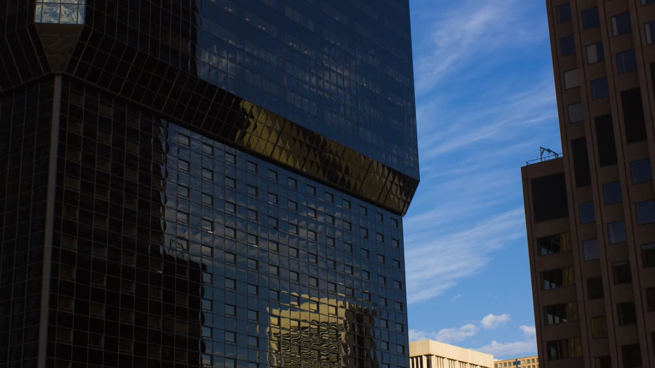 reflejo del cielo azul con nubes en el exterior de vidrio de un edificio moderno en el centro de colorado springs, colorado